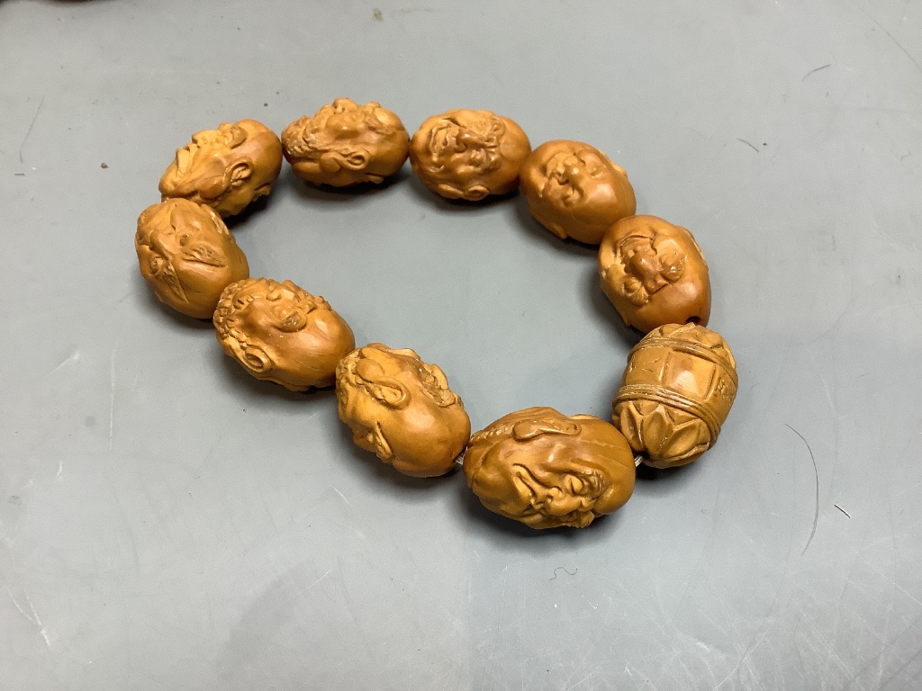 A Chinese peach stone or nut bead necklace, bracelet, a pair of earrings and two carved beads